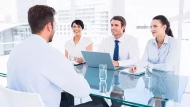 Business meeting in a modern office with four people around a table.