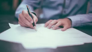 Person writing on paper with a pen.